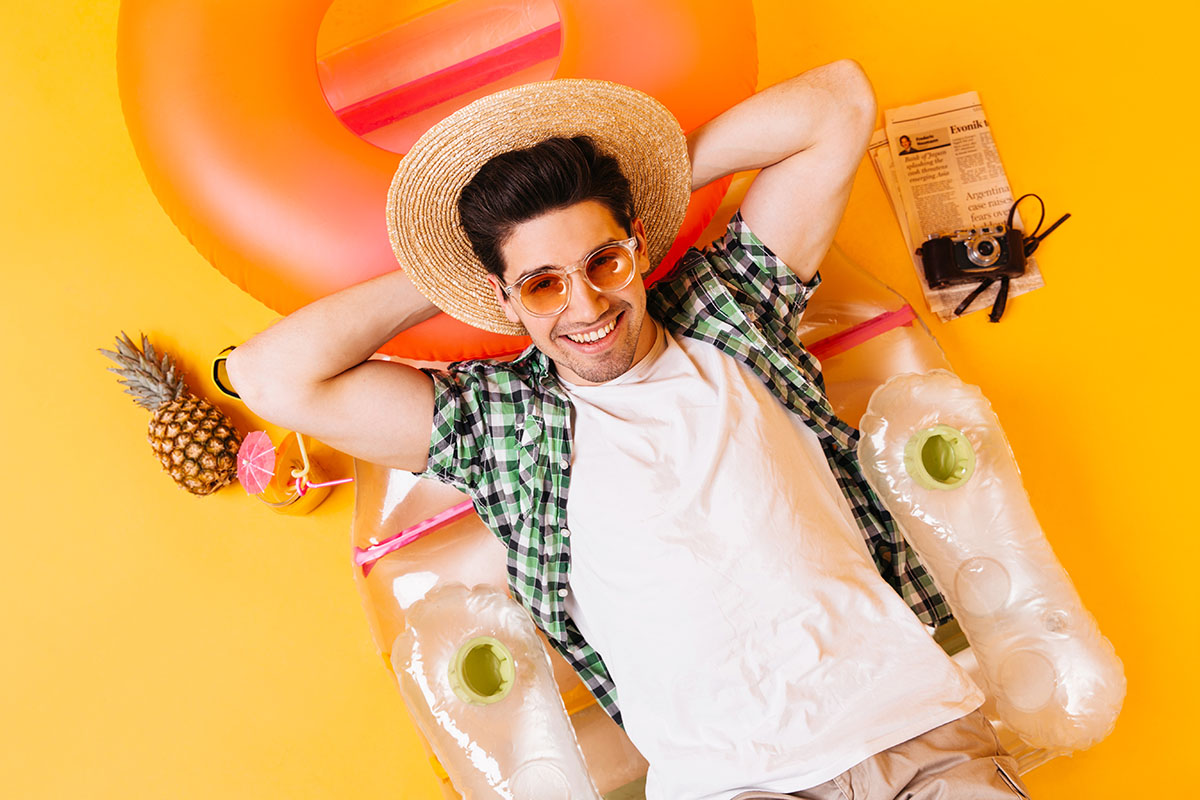 guy straw hat glasses white t shirt is resting inflatable mattress with pineapple cocktail retro camera